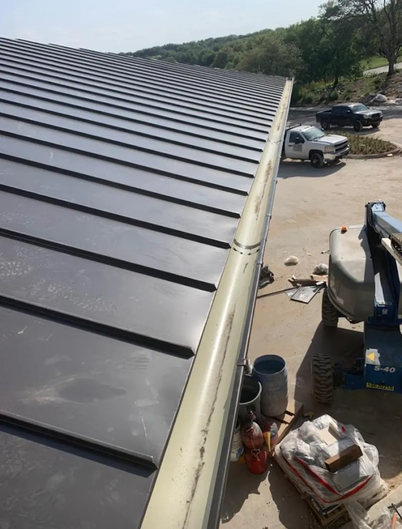 Standing seam panel and gutter detail on a metal roofing jobsite in Wrentham